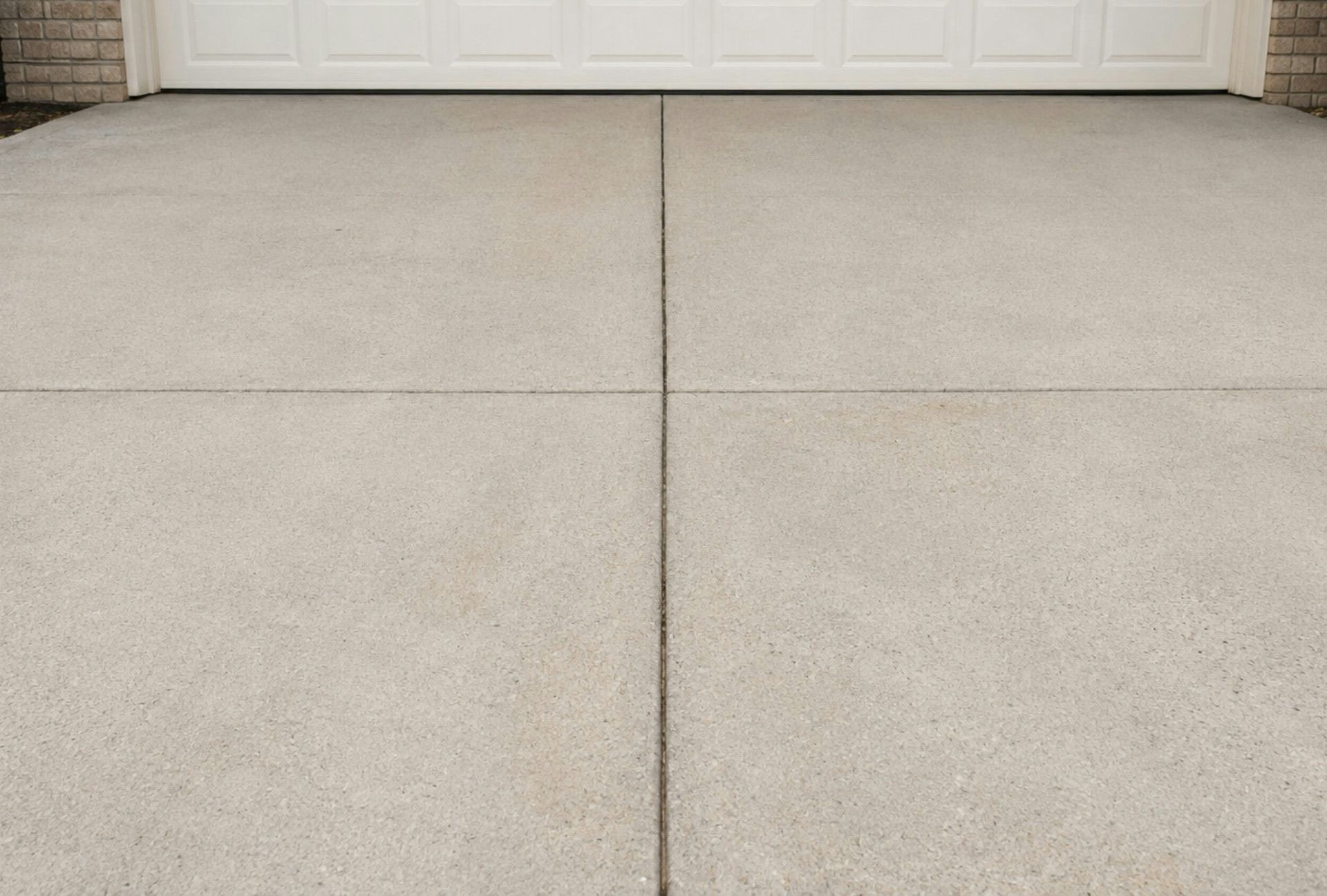 A concrete driveway in front of a white garage door.